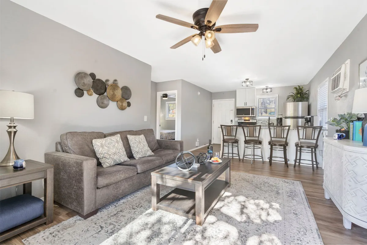 A welcoming living area with a comfortable sofa, coffee table, and a view into the kitchen bar area. The space is arranged for relaxation, family gatherings, or extra sleeping accommodations.
